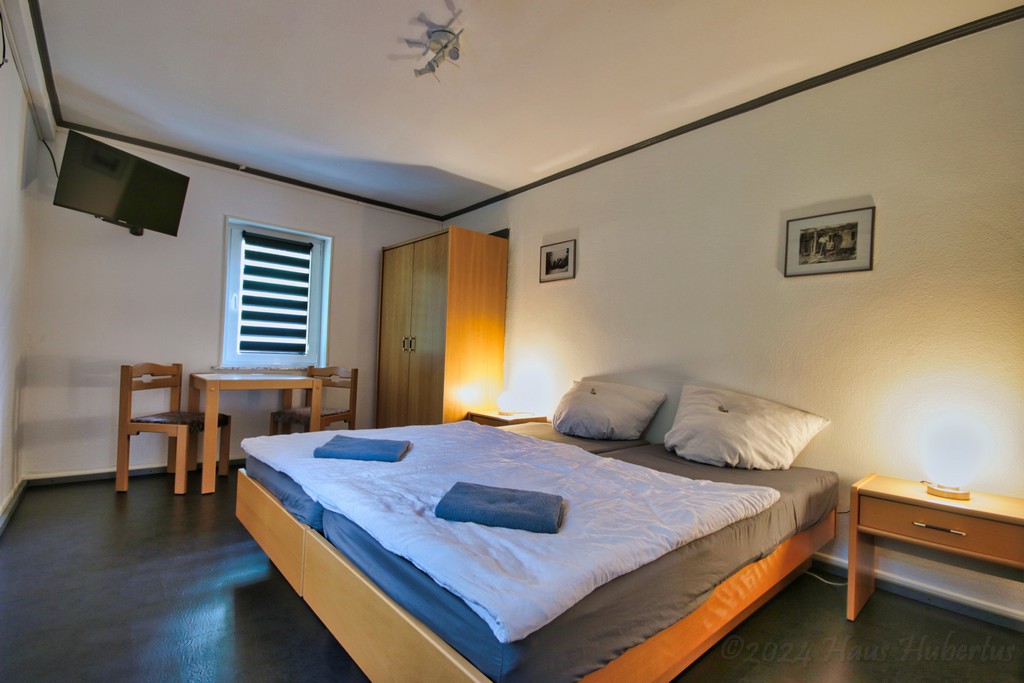 Das doppel Bett des Familienzimmer mit Schrank einem Tisch mit 2 Stühlen und Nachtischen mit Nachtischlampen. Das doppel Bett des Familienzimmer mit Schrank einem Tisch mit 2 Stühlen und Nachtischen mit Nachtischlampen.